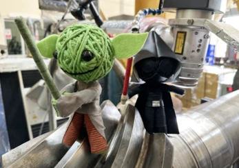 Baby Yoda and Darth Vader figures posed on welded metal pipework